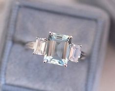 an emerald cut ring with three baguettes sits in a velvet box on the table