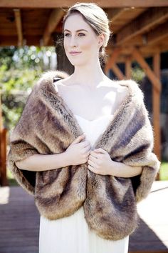 a woman in a white dress is wearing a fur shawl and posing for the camera