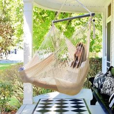 a woman sitting in a hammock chair on the porch with black and white checkered rug