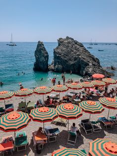 many umbrellas are set up on the beach for people to sunbathe in