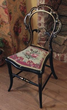 an antique chair with floral fabric on it in front of a brick wall and fireplace