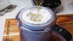 a blender filled with whipped cream on top of a wooden cutting board