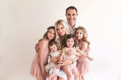 a man is posing with his family in front of a white background for a photo