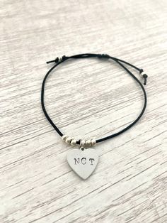 Show your love for NCT (and all subunits!) with this minimalist delicate cord bracelet featuring a hand stamped metal tag and silver glass beads. Choose from a round or heart shaped tag. The bracelet is adjustable up to 8 inches. Please message me if you would like a different size. Each bracelet is handmade and may differ slightly from what is shown in the pictures.  Note: Free shipping does not include tracking. Orders over $35 include free tracked shipping! All orders include a free photocard! Let me know if you would prefer one of your bias or you'll receive a random one. Minimalist Adjustable Beaded Bracelets With Heart Charm, Simple Adjustable Hand Stamped Jewelry, Adjustable Heart Shaped Sterling Silver Beaded Bracelet, Adjustable Nickel-free Sterling Silver Friendship Bracelets, Adjustable Heart Bracelet With Sliding Knot For Everyday, Adjustable Hypoallergenic Sterling Silver Heart Bracelet, Minimalist Adjustable Heart Bracelet For Everyday, Sterling Silver Adjustable Friendship Bracelets, Adjustable Minimalist Heart Bracelet For Everyday