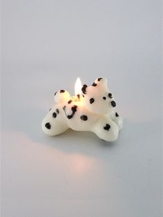 a candle that is shaped like a dog with black spots on its face and legs