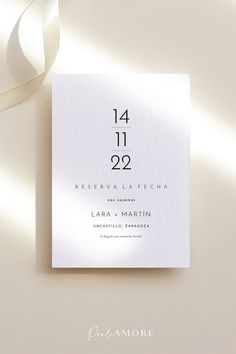 a white wedding card with the number two on it and a satin ribbon around it