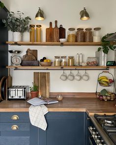 a kitchen with open shelving and wooden counter tops, blue cabinets and brass knobs