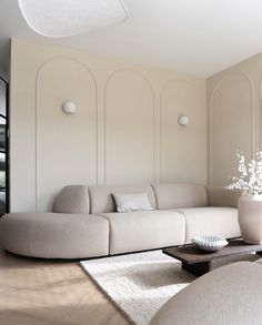 a living room filled with furniture and a large white vase on top of a coffee table