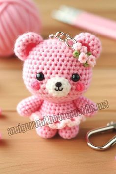 a pink teddy bear keychain sitting on top of a table next to a pair of scissors