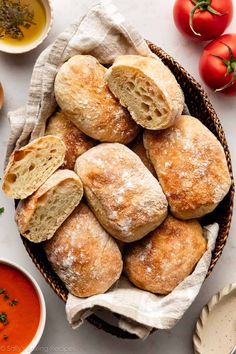 bread rolls in a basket with tomatoes and dipping sauces