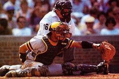 a baseball player sliding into home plate with the catcher and umpire behind him, in front of an audience