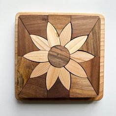 a wooden square with a flower design on the front and center, sitting on a white surface