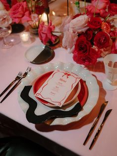 the table is set with plates, silverware and flowers