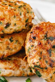 three crab cakes stacked on top of each other with herbs and seasoning around them