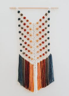 a crocheted wall hanging with multicolored beads and tassels on it