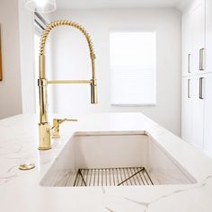 a white kitchen with gold faucet and sink