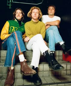 three young men sitting on steps with their legs crossed and one man in yellow sweater