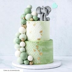 a three tiered cake with an elephant topper and beads on the bottom layer