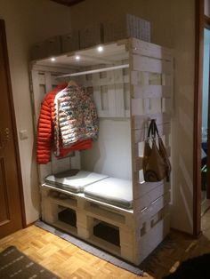 a room with a bed made out of pallets and some bags hanging on the wall