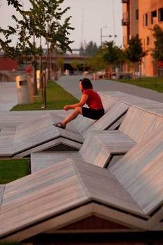 a woman sitting on top of a wooden bench in the middle of an open area