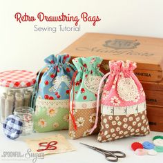 three small draws bags sitting on top of a table next to sewing needles and buttons