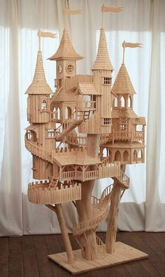 a wooden model of a castle made out of wood sticks and rope, sitting on top of a hard wood floor