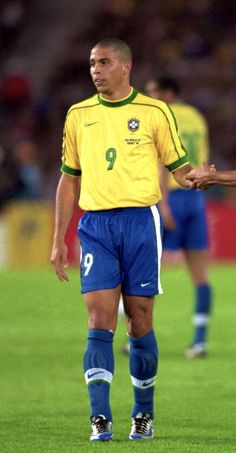 a man standing on top of a soccer field wearing a yellow shirt and blue shorts