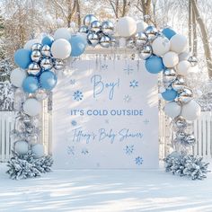 a blue and white winter themed baby shower with balloons, snowflakes and decorations