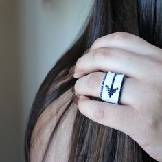 a woman's hand with a white and black beaded ring on her finger