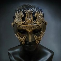 a black and gold mask on a mannequin's head in front of a dark background