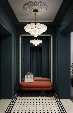 an orange couch sitting under a chandelier next to a black and white floor