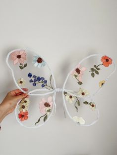 a person holding up a butterfly made out of string and flowers