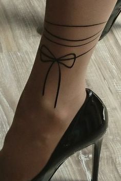 a woman's foot with a tattoo on her left ankle and a black high heel shoe