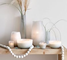 candles and vases sit on a table with beads around the edges, along with other decorative items