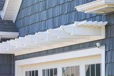 a white gutter attached to the side of a blue house with windows and shutters