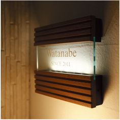 a wooden shelf with a glass plaque on it that reads, vattanabe