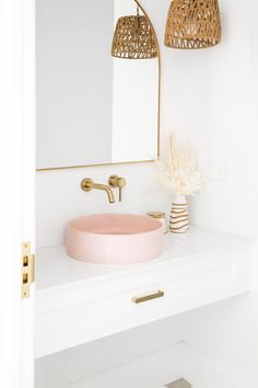 a bathroom with a pink sink and gold faucet on the counter next to a mirror