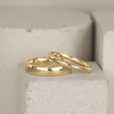 two yellow gold wedding rings sitting on top of each other in front of a white background