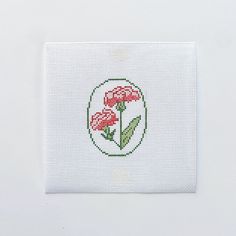 a cross - stitch card with three red flowers in a circle on it's side