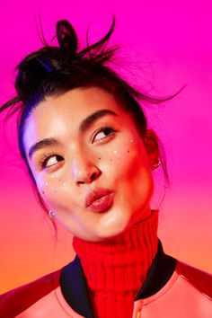 a woman with her hair blowing in the wind, wearing a red turtle neck sweater