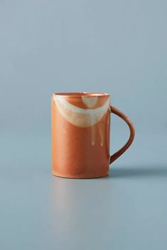 an orange coffee mug sitting on top of a table