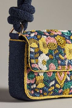 a blue purse with flowers on it and a chain hanging from the front, sitting on a gray surface