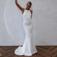 a woman in a white wedding dress is holding her arm up to the side while standing on a wooden floor