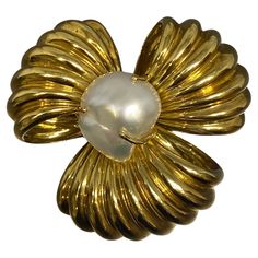 Luxurious large brooch featuring a large white baroque pearl at the center of ribbed looped ribbons of 18k yellow gold. Baroque pearls are known for their irregular, non-spherical shapes, which give them a distinct and often dramatic appearance. This type of pearl, combined with the warm luster of 18k yellow gold, creates a piece that is both classic and striking. Back is fitted with a locking trombone clasp and double prongs, allowing for better attachment to clothing. Baroque pearls are prized Gold Baroque, Trombone, Baroque Pearls, Large White, Jewelry Collection, Ribbon, Yellow Gold, Texture, Yellow