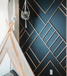 a teepee tent in the corner of a room with black walls and geometric patterns