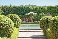 an outdoor dining area is surrounded by hedges