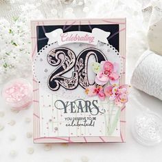 a close up of a card on a table with flowers and yarns in the background