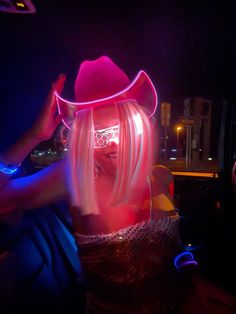 a woman with blonde hair wearing a pink cowboy hat and glowing eye glasses in the dark