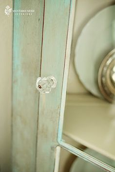 an old cabinet with glass knobs and a clock in the backgrouund