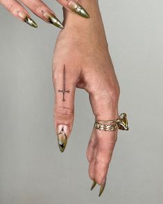 a woman's hand with gold nail polish and cross tattoo